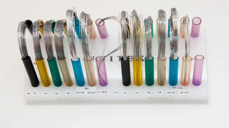 Display of colorful orthodontic wires arranged neatly on a stand.