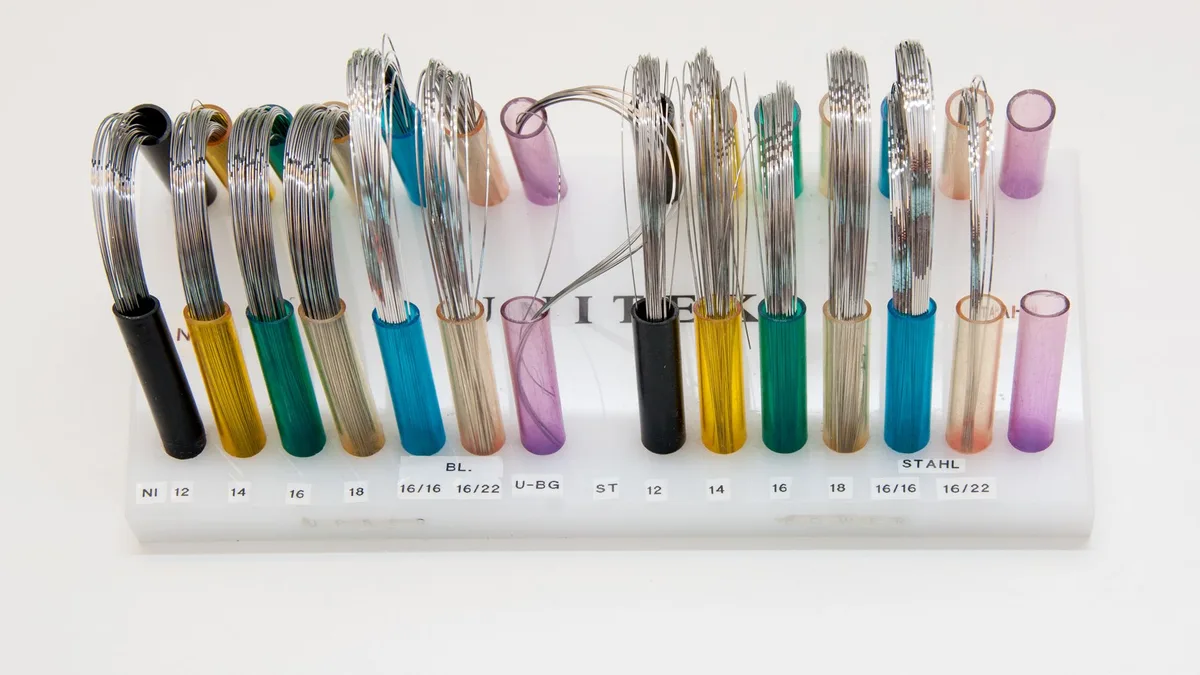 Display of colorful orthodontic wires arranged neatly on a stand.