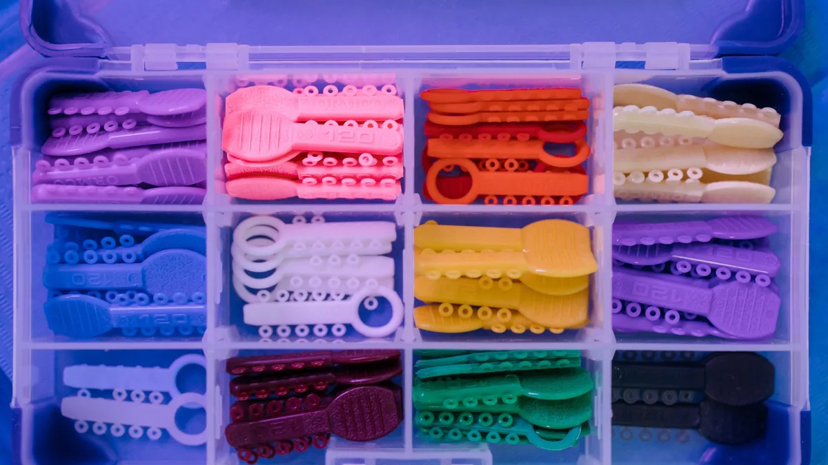 Close-up of a multicolored dental tools set in an organized box, showcasing various orthodontic elastics.