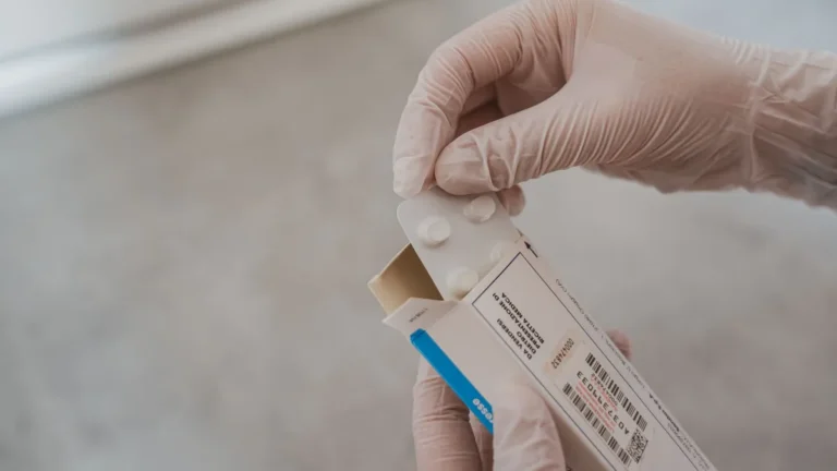 Close-up of hands in gloves handling medication blister pack, ensuring safety and hygiene in healthcare.