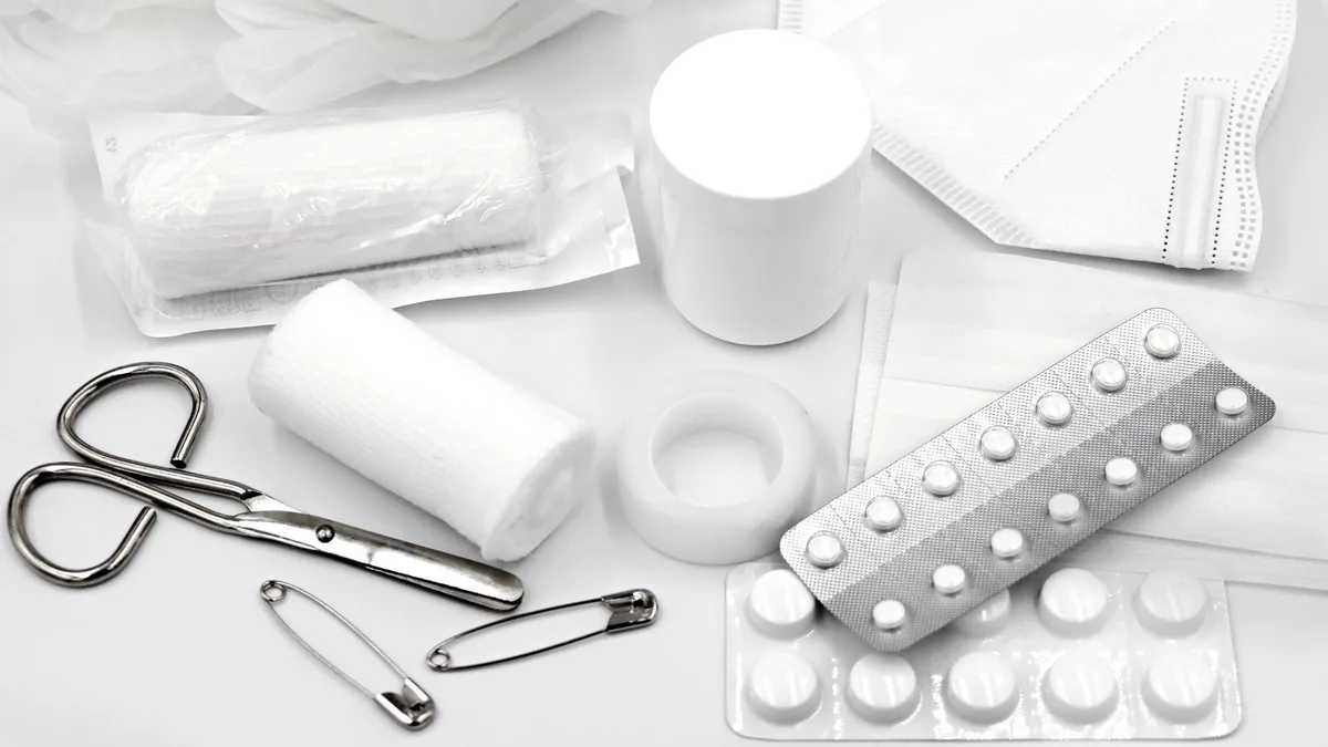 A flat lay of essential first aid supplies and medical equipment on a white background.