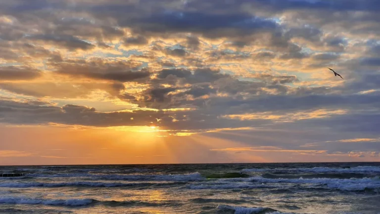 Gorgeous sunset over the ocean at Dziwnówek Beach, Poland with dramatic clouds and waves.