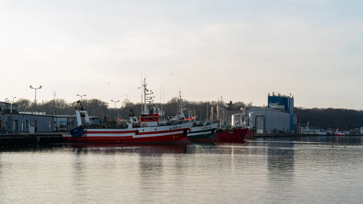 A serene view of fishing boats docked in the Kołobrzeg harbor, Poland during daytime.